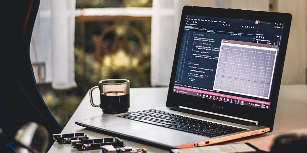 A laptop on the desk next to a coffee mug