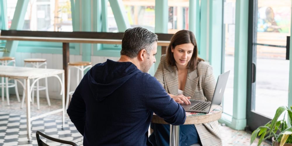 Businessman and businesswoman having a meeting in a cafe over a laptop