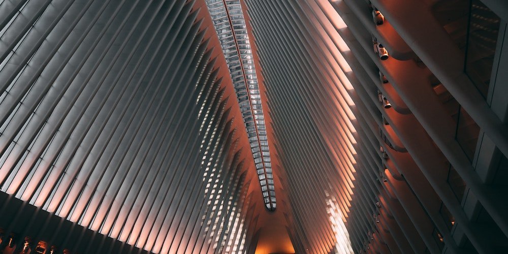 Lobby of a modern office building shot from below with the pillars on the side lit up by a soft red light